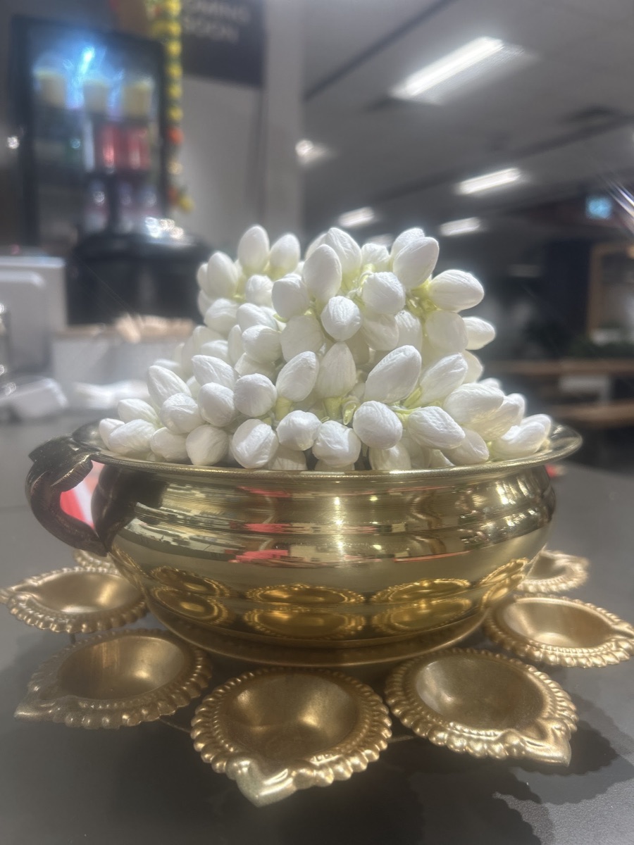 Fresh Madurai jasmine in a brass urli with lamps at Madurai Masala Dosa Kadai